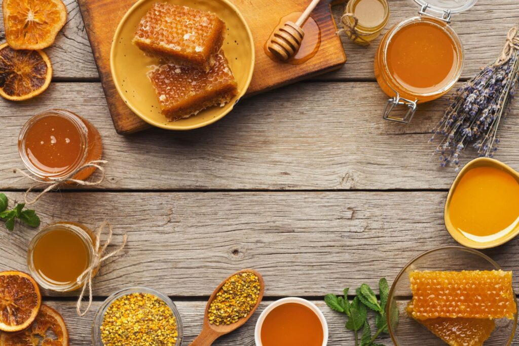 différents types de miels avec des plantes sur une table en bois
